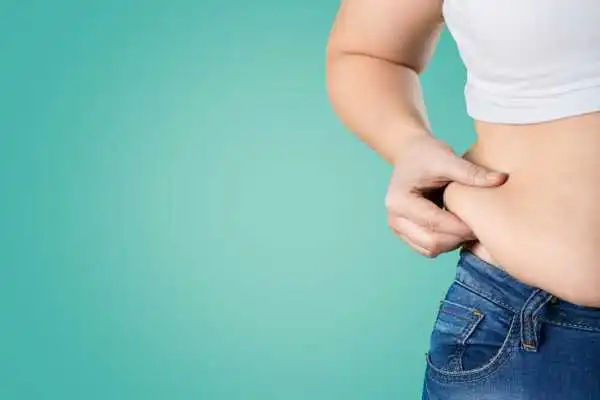 Image of woman pinching her love handles to show weight gain Bridport